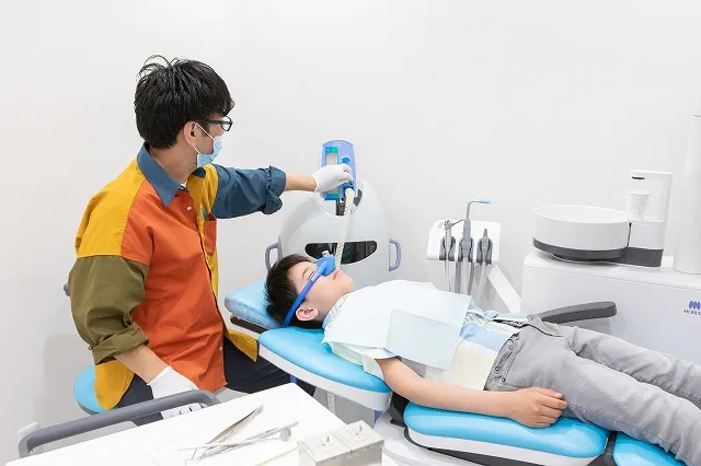笑気麻酔装置を付けている患者と機械を操作する歯科医師