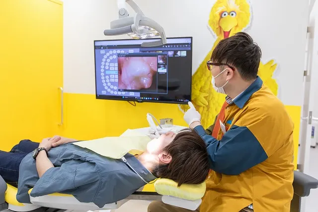患者の治療中、歯科医師がモニターを見せながら説明している風景