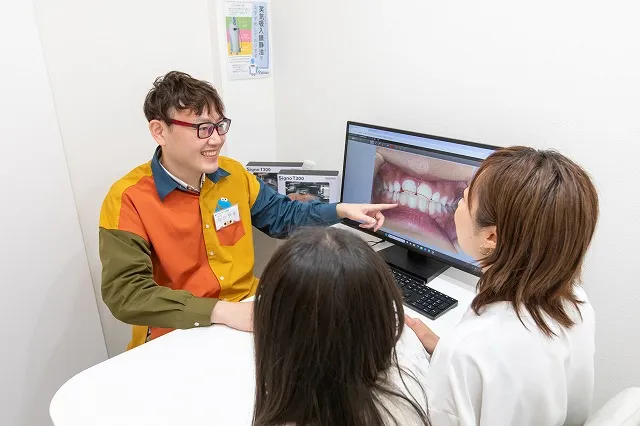 歯科医師がモニターを指しながら患者に説明する姿